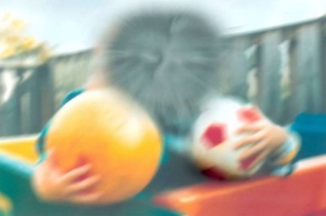 Two boys with balls and the centre of the picture is obscured but the outer portion is blurred but can be seen.