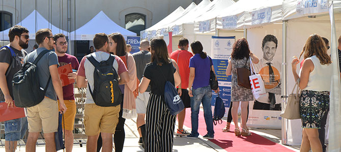 Varias personas ante stands de empresas que están recogiendo curriculums e informando de las ofertas de empleo disponibles.